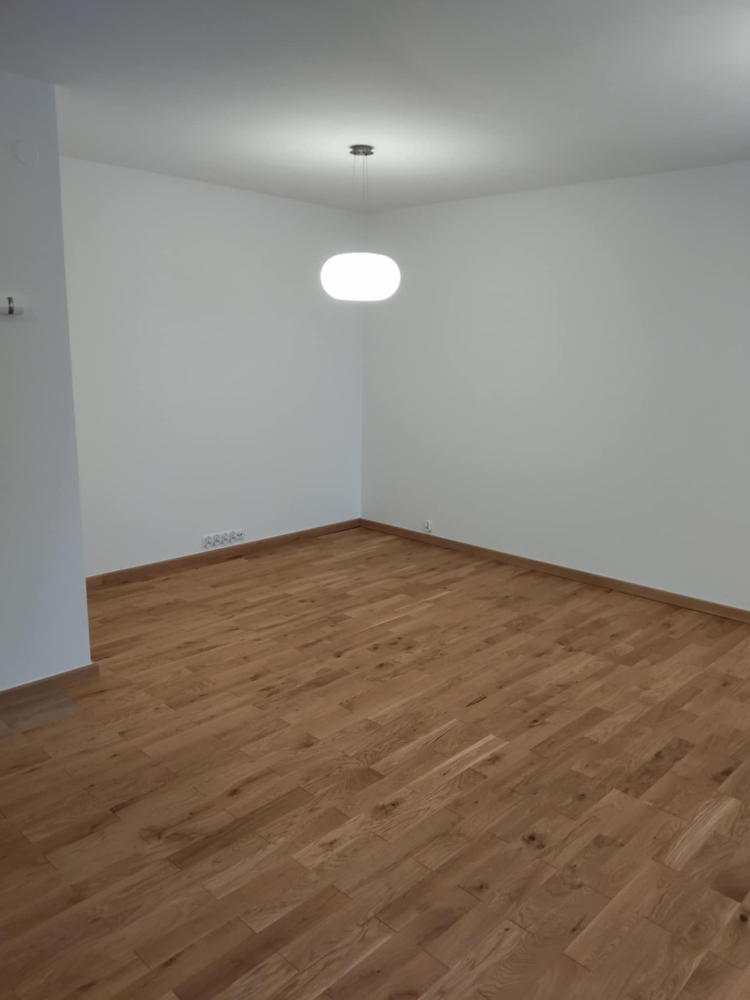 Naturalna podłoga drewniana ułożona w przestronnym pokoju z dopasowanymi listwami wykończeniowymi